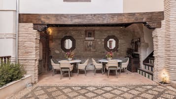 An outdoor patio with stone walls, a tiled floor, and a table with chairs.