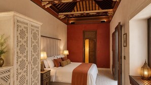 A bedroom with a bed, nightstands, a decorative cabinet, a mirror, and a wall-mounted light fixture. - YANGUAS NAZARI PALACE (Granada)