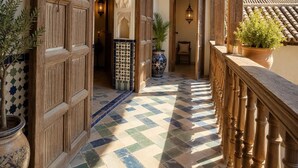 A corridor with a tiled floor, wooden doors, and a balcony with a railing. - YANGUAS NAZARI PALACE (Granada)