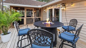 A wooden deck with a round table and four chairs, surrounded by potted plants. - Folly Fun House – Just Steps to the Beach (Folly Beach)