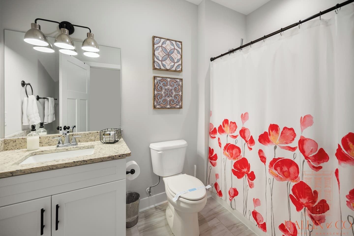 A bathroom with a white toilet, a sink with a mirror, and a shower curtain with a floral pattern.