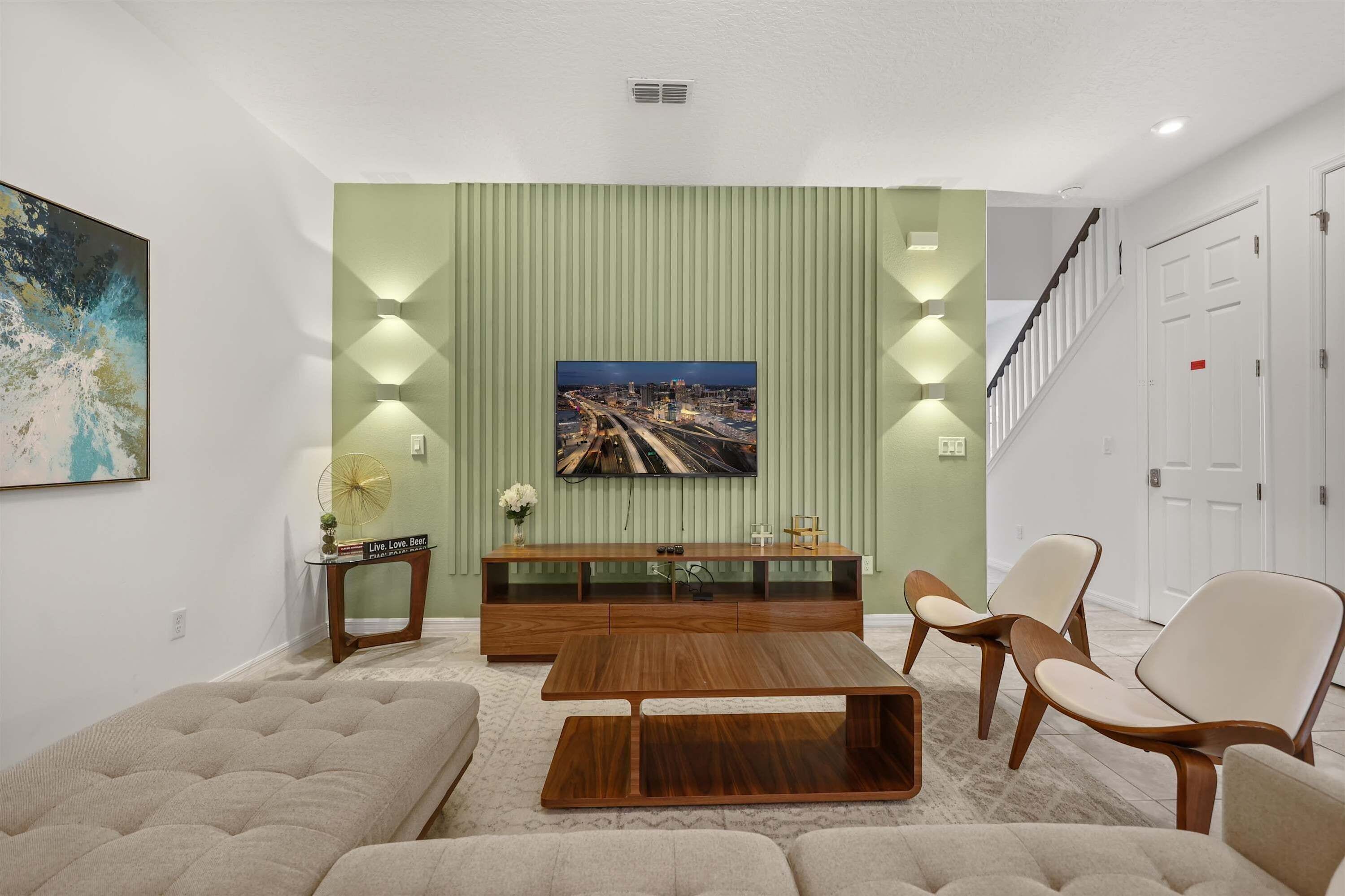 Una sala de estar moderna con un sofá, una mesa de centro, un televisor en la pared y una escalera.