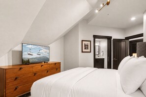Une chambre à coucher avec un lit, une commode en bois et un téléviseur diffusant une vue sur la montagne.