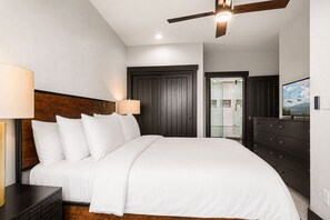 Ein Schlafzimmer mit einem Bett, einem Nachttisch, einer Kommode, einem Deckenventilator und einer Tür zu einem Badezimmer.