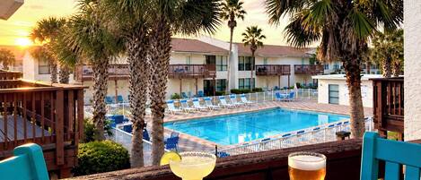 Une vue sur la piscine, avec une table, des chaises et une boisson.