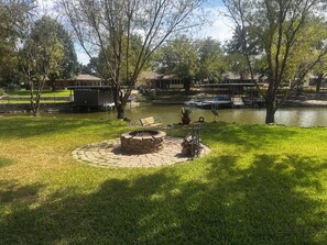 Ein Park mit Feuerstelle, Bänken und einem Gewässer.