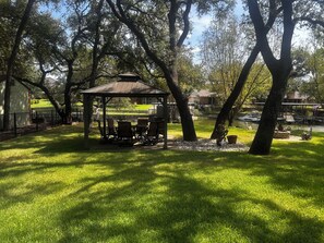 A gazebo with seating, surrounded by trees and a grassy area. -  Lake Granbury Waterfront Cottage! 2 miles from Downtown with private boat dock! (Granbury)