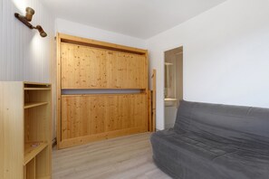 Ein Zimmer mit grauem Sofa, Holzschrank und Spiegel.