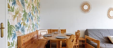 A dining area with wooden furniture, a patterned wall, and two wall-mounted sunburst decorations.