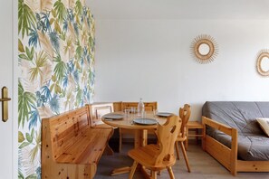 Ein Essbereich mit Holzzmöbeln, einer Wand mit Muster und zwei sonnenstrahlartigen Wanddekorationen.