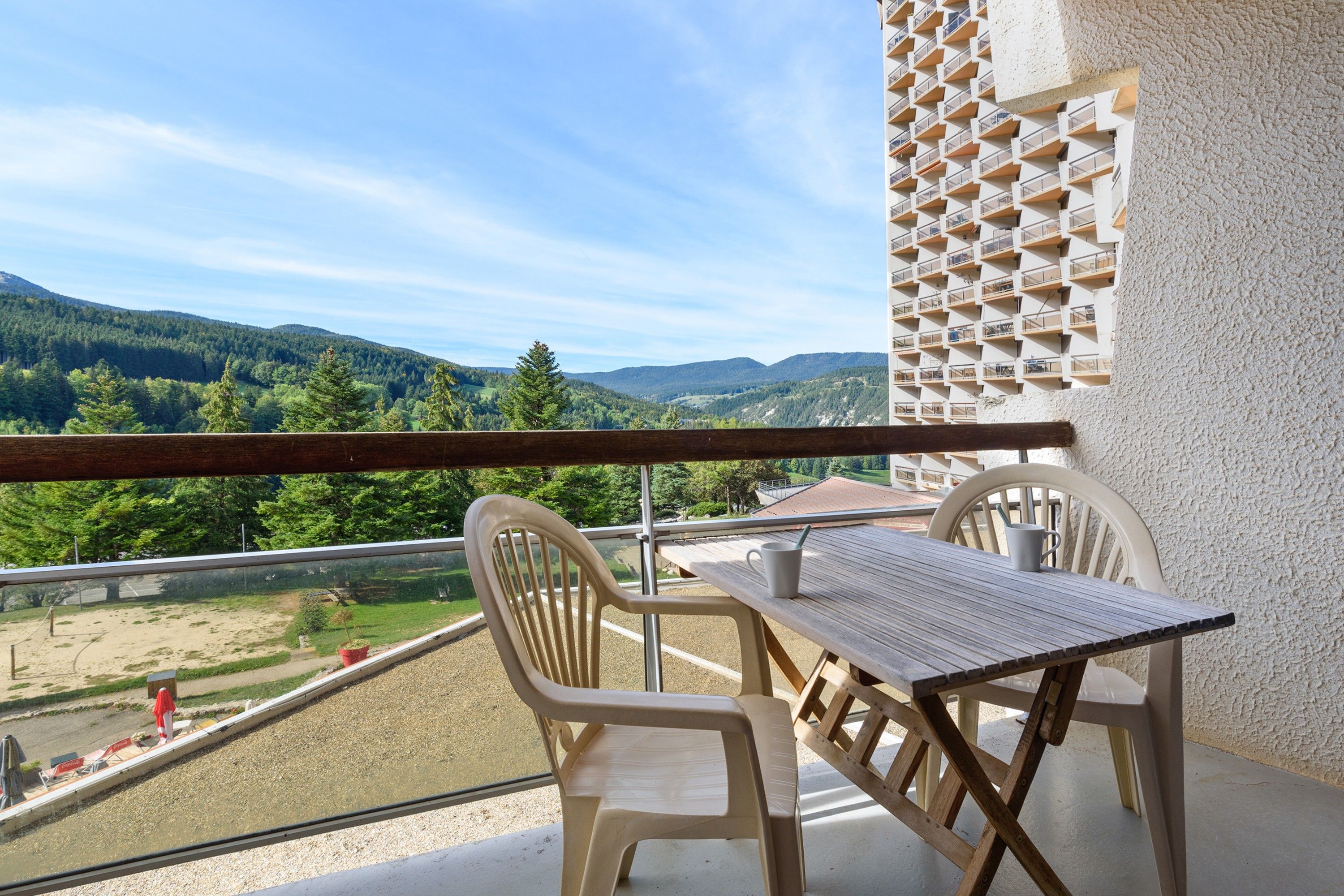Een balkon met een tafel en stoelen, met uitzicht op een bergachtig landschap.