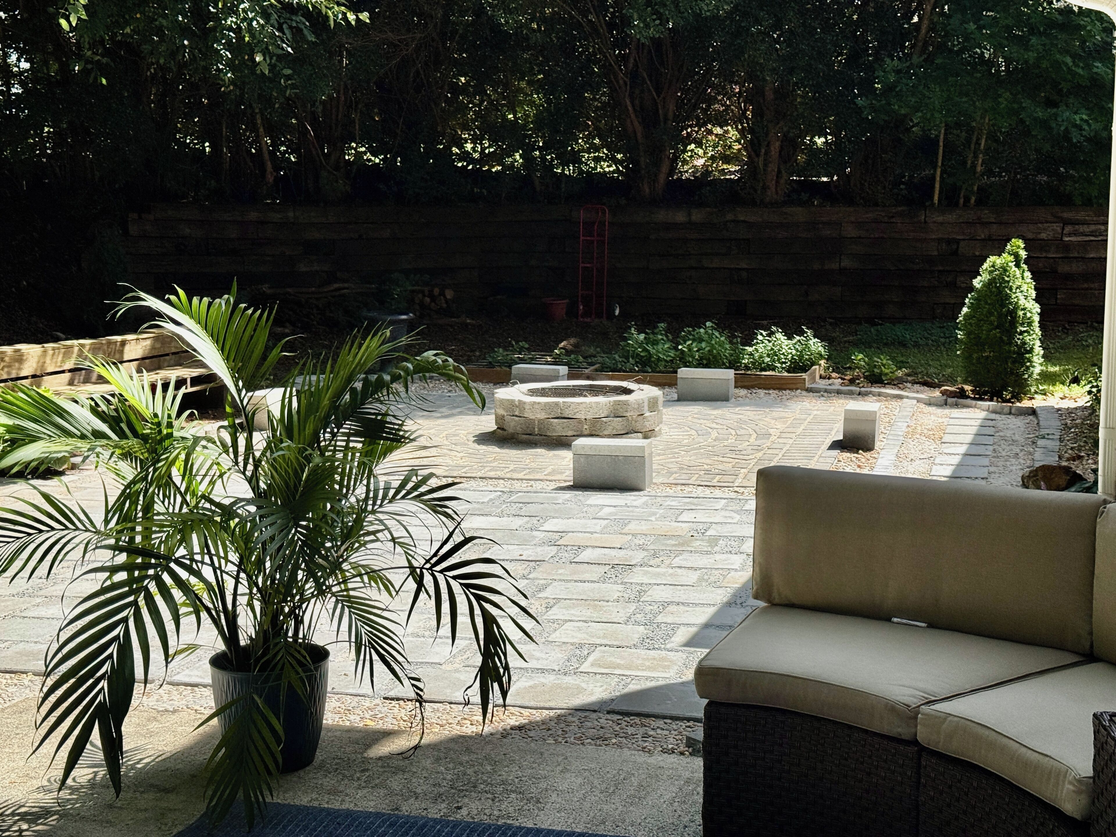 Un espace patio agrémenté d’un foyer en pierre, de mobilier d’extérieur et de plantes en pot.