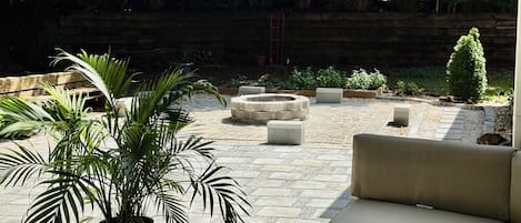 A patio area with a stone fire pit, outdoor furniture, and potted plants.