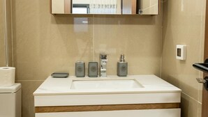 A bathroom with a white sink, a mirror above it, and three bottles of soap on the counter. - Cozy & Bright 2-Room Apartment in Dakar (Dakar)