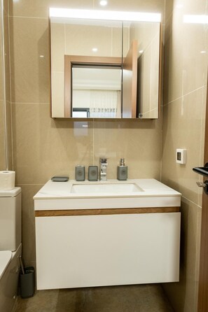 A bathroom with a white sink, a mirror above it, and three bottles of soap on the counter. - Cozy & Bright 2-Room Apartment in Dakar (Dakar)