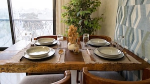 A dining table set with plates, cutlery, and a vase with dried flowers. - Cozy & Bright 2-Room Apartment in Dakar (Dakar)