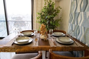 A dining table set with plates, cutlery, and a vase with dried flowers. - Cozy & Bright 2-Room Apartment in Dakar (Dakar)