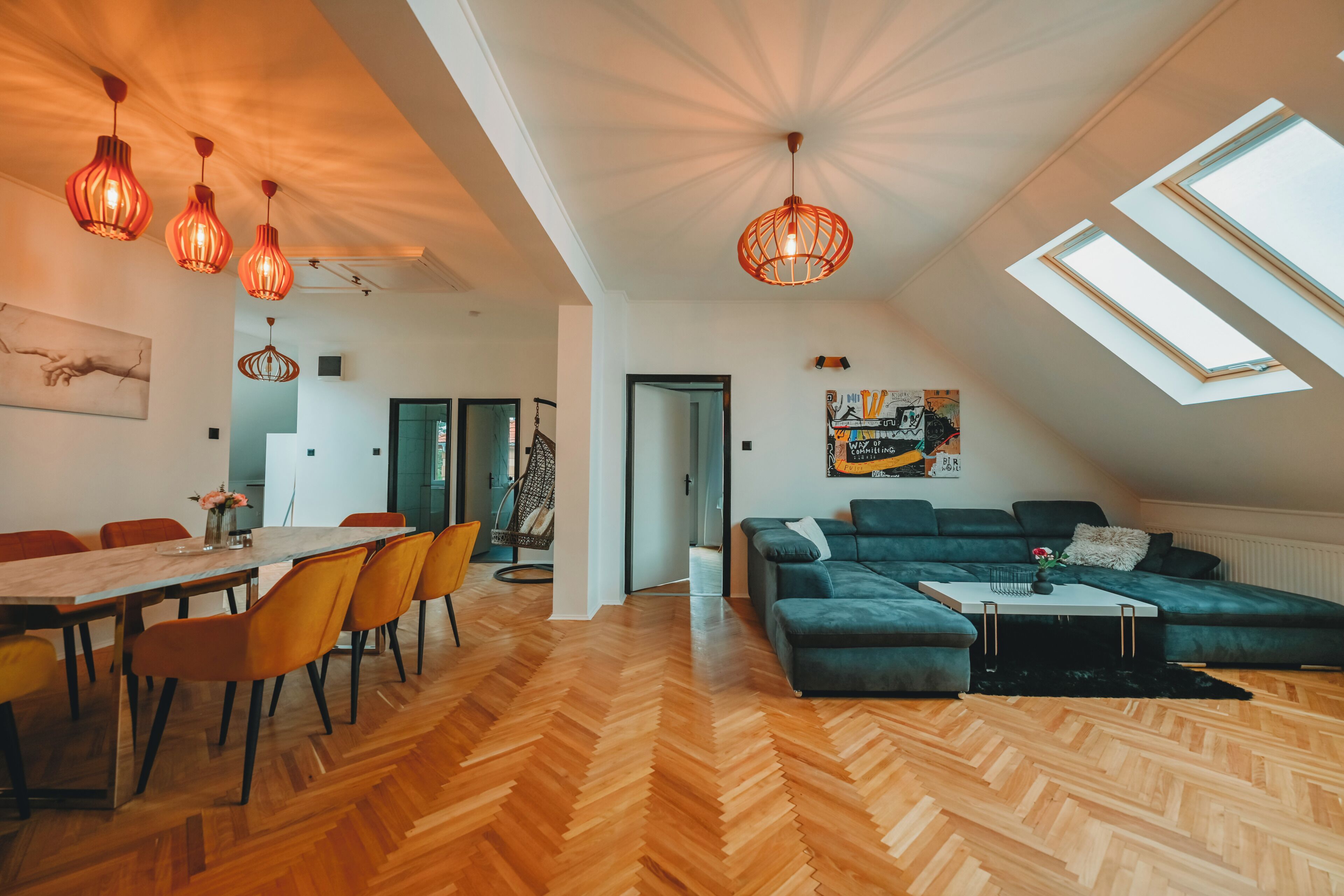 Um interior moderno com área de refeições, sala de estar com sofá e mesa de centro, e um claraboia.