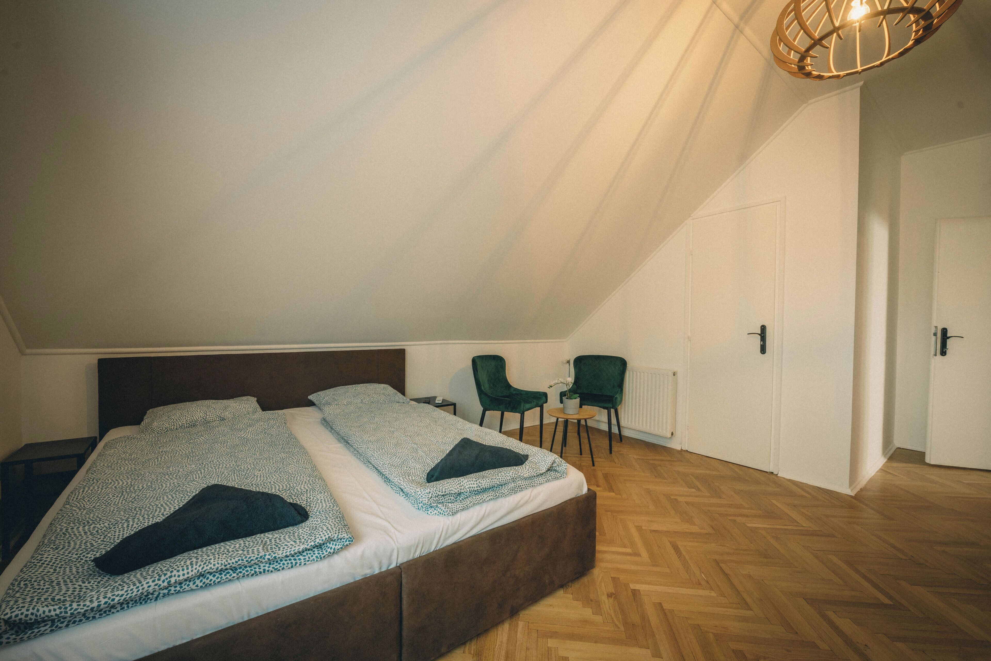 Une chambre à coucher avec un grand lit, deux chaises, une petite table et un radiateur.