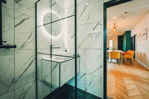 A modern bathroom with a glass-enclosed shower, a marble-tiled wall, and a round mirror. - Modern 4-bedroom vacation rental with a garden in Siófok; dog-friendly (Siófok)