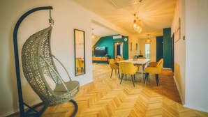 A room with a hanging chair, a dining area with chairs, and a herringbone wooden floor. - Modern 4-bedroom vacation rental with a garden in Siófok; dog-friendly (Siófok)