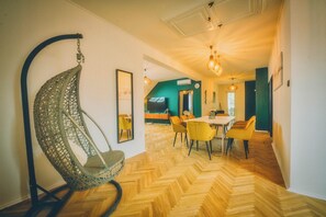 A room with a hanging chair, a dining area with chairs, and a herringbone wooden floor. - Modern 4-bedroom vacation rental with a garden in Siófok; dog-friendly (Siófok)