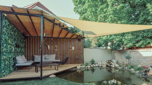 A covered outdoor seating area with a pool and a stone wall. - Modern 4-bedroom vacation rental with a garden in Siófok; dog-friendly (Siófok)