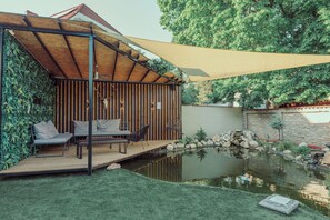 A covered outdoor seating area with a pool and a stone wall. - Modern 4-bedroom vacation rental with a garden in Siófok; dog-friendly (Siófok)