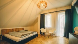 A bedroom with a bed, two chairs, a table, a hanging light fixture, and a window with curtains. - Modern 4-bedroom vacation rental with a garden in Siófok; dog-friendly (Siófok)