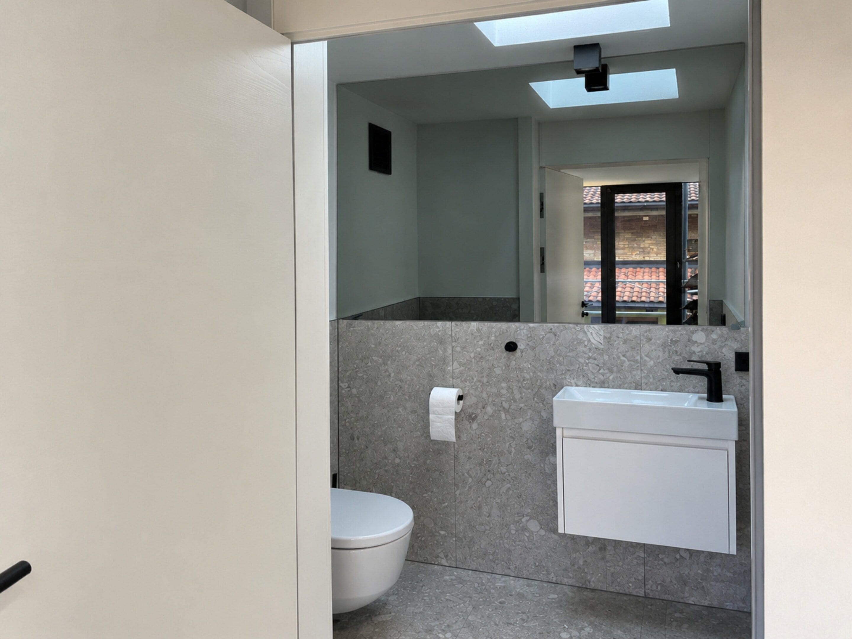 Ein modernes Badezimmer mit Dachfenster, Toilette und Waschbecken mit Spiegel.