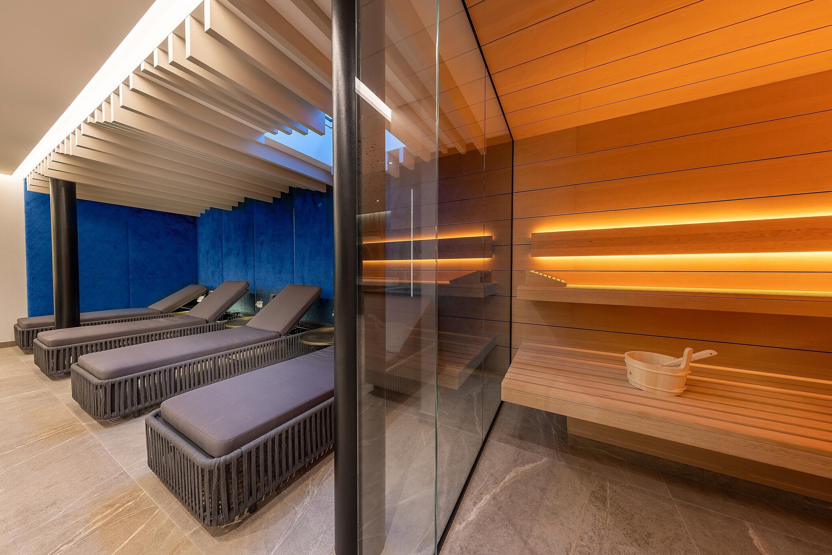 Et moderne spa-område med massagestole, en glasvæg og træpaneler.