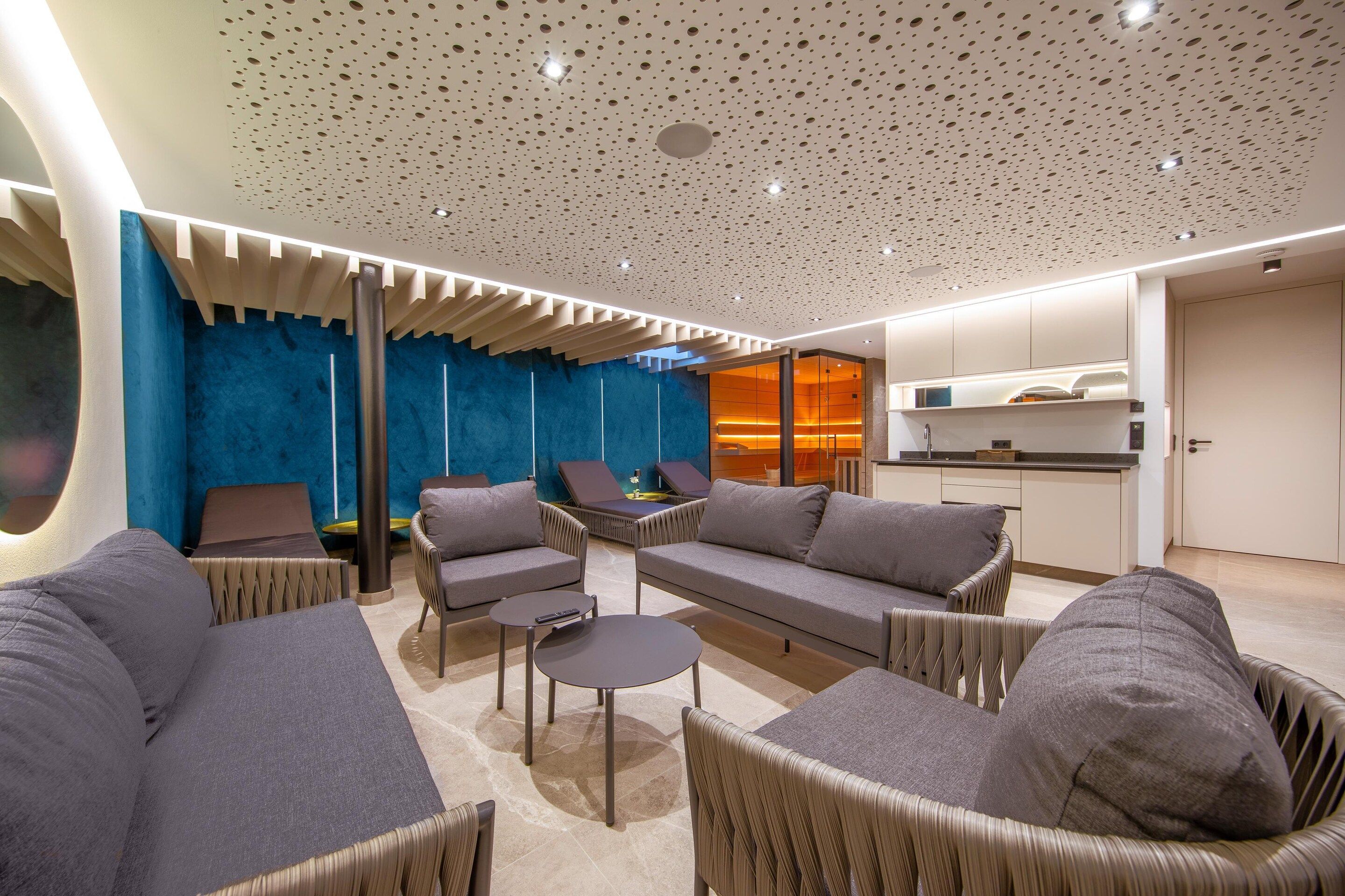 Un intérieur moderne comprenant un coin salon, une cuisine et un mur d’accent bleu.