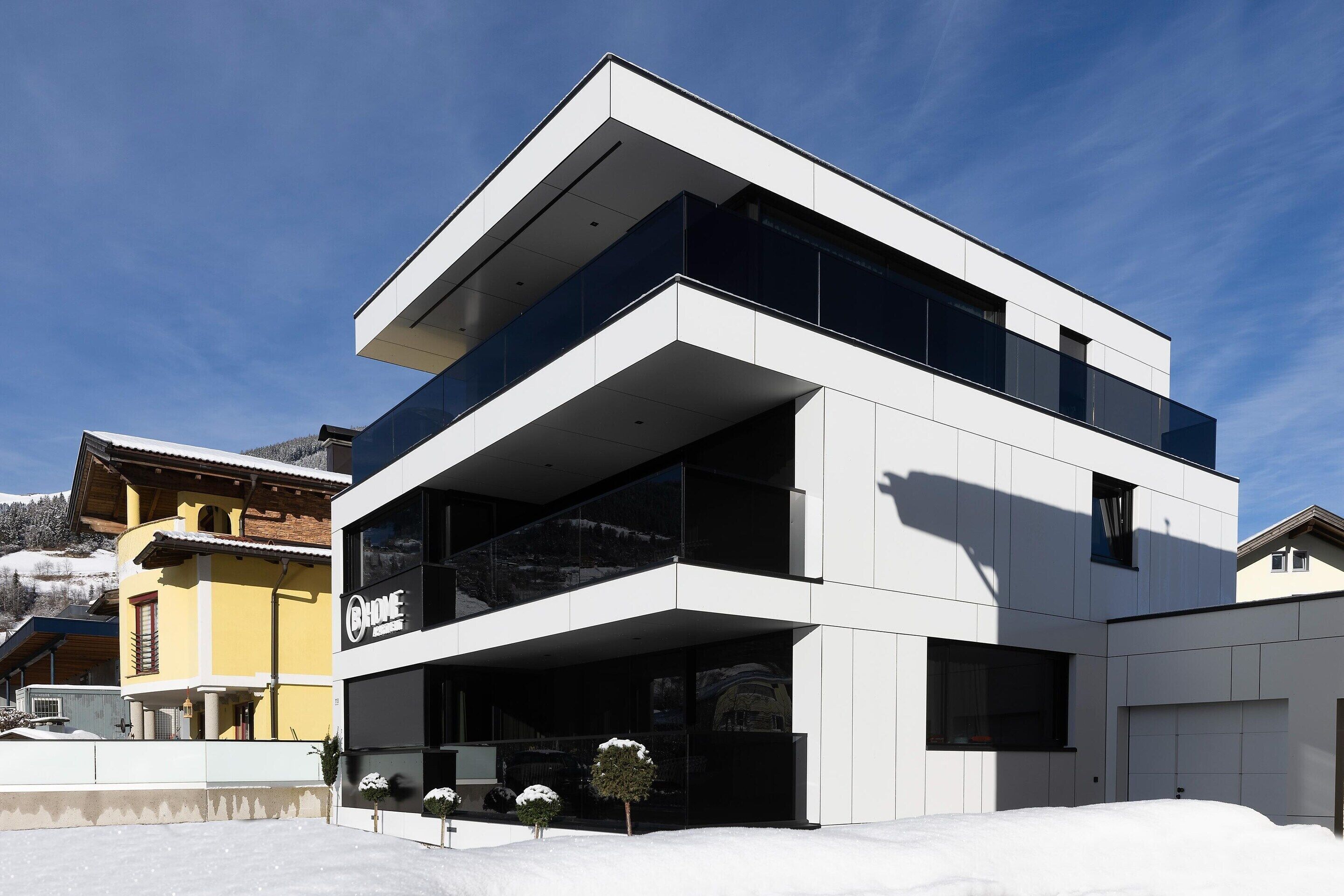 A modern two-story building with a flat roof and large windows.