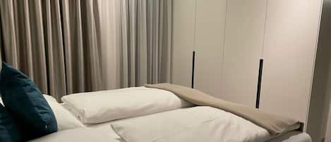 Quarto com cama, cortinas e guarda-roupa.