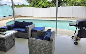 An outdoor patio with wicker furniture and a pool. - Family Pool Retreat - Sleeps 8 - Pet Friendly (Tampa)