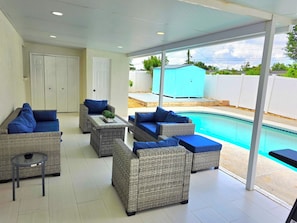 A covered outdoor seating area with wicker furniture and a pool. - Family Pool Retreat - Sleeps 8 - Pet Friendly (Tampa)