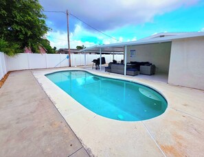 A swimming pool with a covered patio area, a white fence, and a tree. - Family Pool Retreat - Sleeps 8 - Pet Friendly (Tampa)