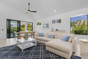 A modern living room with a sofa, coffee table, and dining area. - Modern Naples Beach Home Pool Hot Tub 2 Master Suites (Naples)