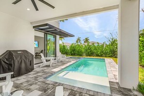 A swimming pool with a patio area, outdoor furniture, and a covered grill. - Modern Naples Beach Home Pool Hot Tub 2 Master Suites (Naples)