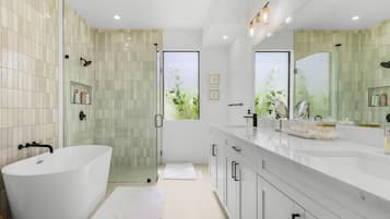 Um banheiro moderno com uma banheira de imersão, box de vidro e uma pia com espelho grande.