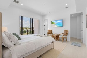 Quarto com cama grande, televisão e vista para o exterior.