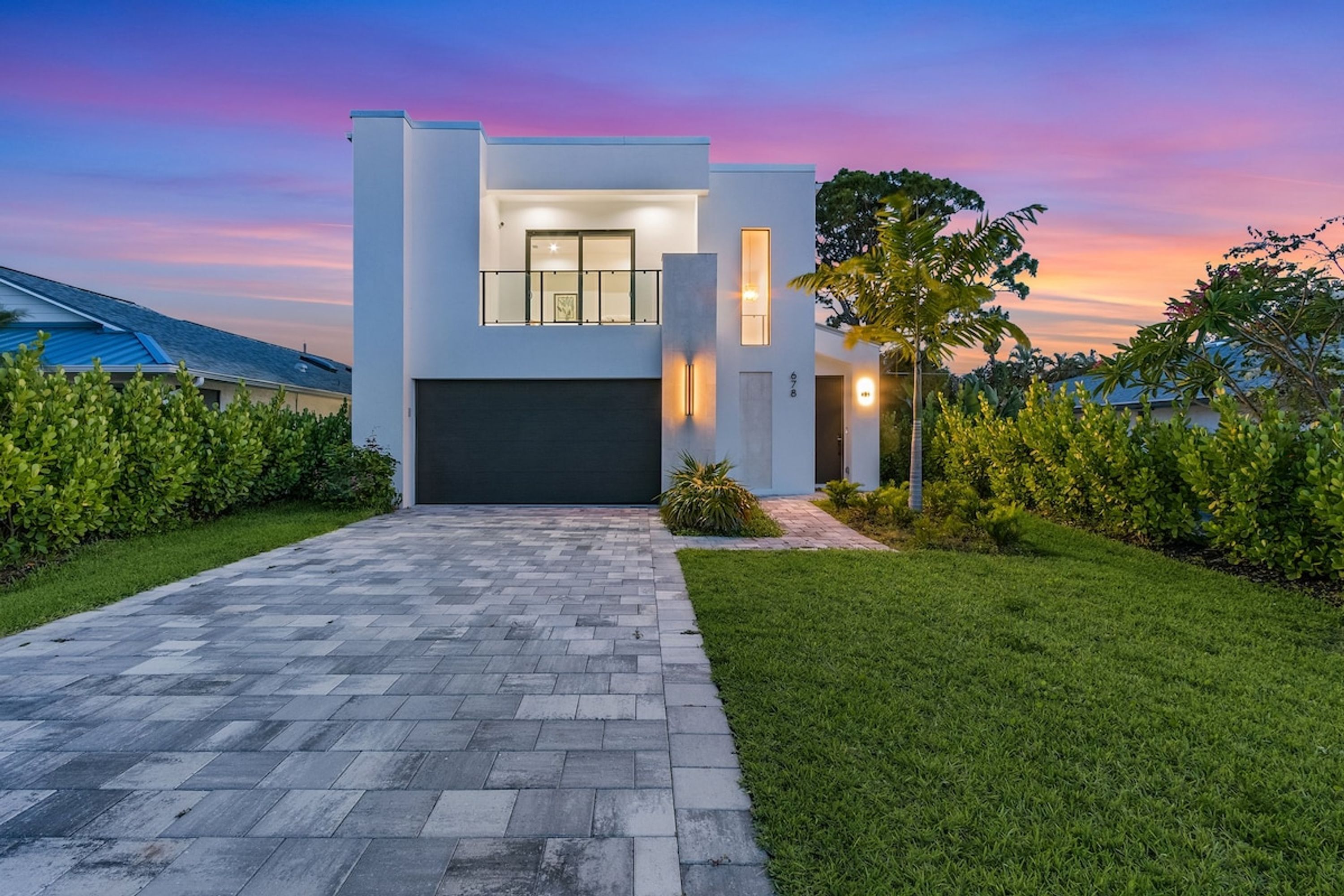 A modern two-story house with a paved driveway leading to a garage.