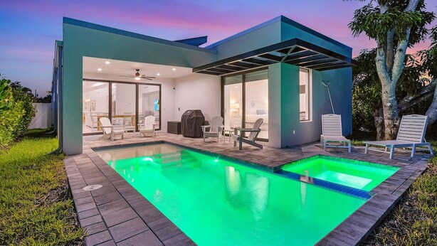 Une maison moderne dotée d’une piscine, d’un espace salon extérieur et d’un patio couvert.