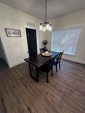 A dining area with a dark wooden table, black chairs, a chandelier, a 'PANTRY' sign, and a 'thankful' sign on the wall. - Nova on Locust, Walking distance to downtown Hendersonville 3Bed/2Bath (Hendersonville)