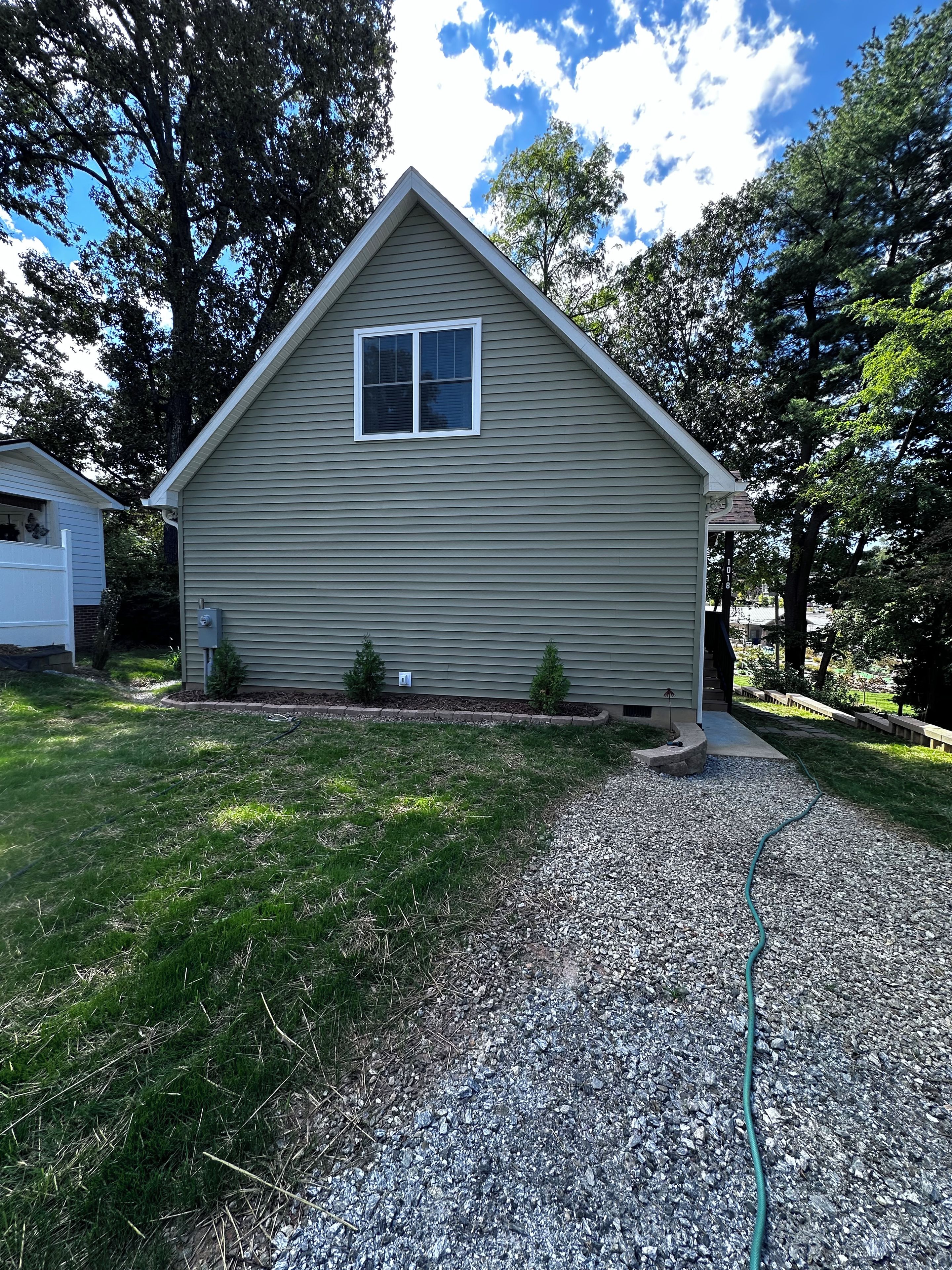 A single-story house with a gabled roof, a front porch, and a gravel driveway.