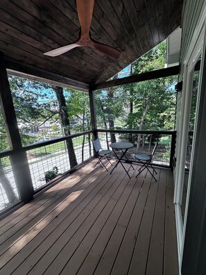 Eine überdachte Veranda mit Deckenventilator, zwei Stühlen und einem Tisch.