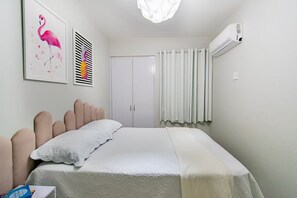 Ein Schlafzimmer mit einem Bett, einer Tür, einer Klimaanlage und zwei Wandbildern.