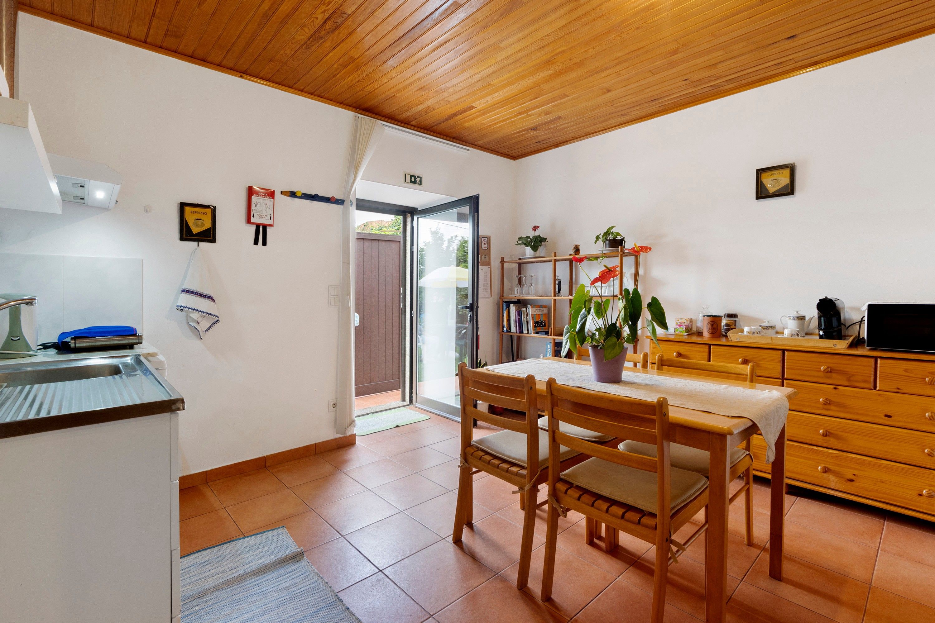 Una cocina con una mesa de madera, sillas y una cafetera.