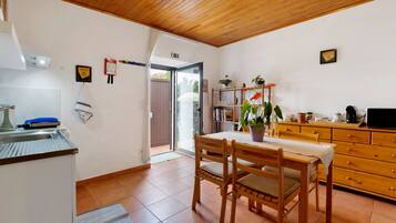 Una cocina con una mesa de madera, sillas y una cafetera.