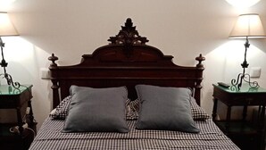 A bed with a checkered bedspread, two pillows, a wooden headboard, and two bedside tables with lamps. - Pêssego - Al Apartment with Mountain View, Wi-Fi, and Air Conditioning (Belece)